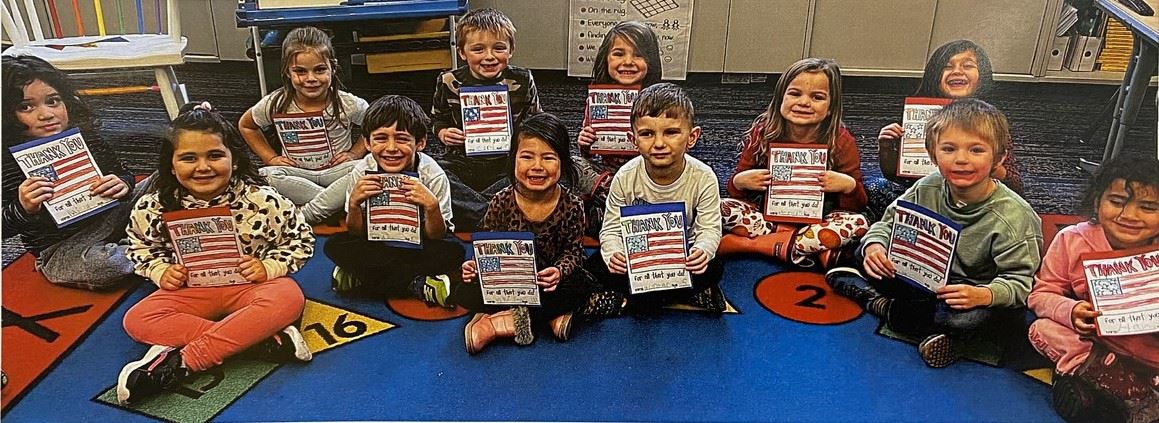 Students in Mrs. Burchin's class hold up cards they made